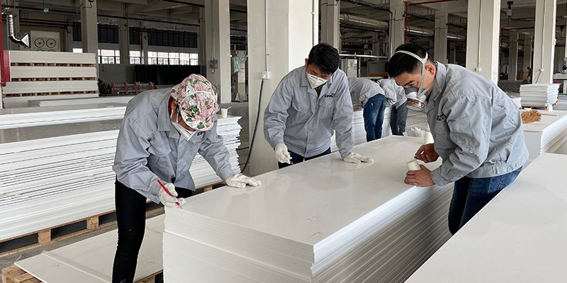 A factory worker inspecting a sheet of modified acrylic solid surface.